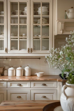 a kitchen filled with lots of white cupboards and counter top covered in pots and pans