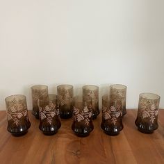 a set of six glasses sitting on top of a wooden table next to each other