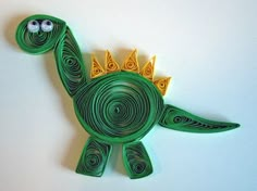 a paper cut out of a green dinosaur with yellow spikes on it's head