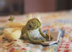 a small stuffed animal sitting on top of a bed next to a notebook and pencil