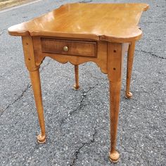 a small wooden table sitting on the side of a road next to a parking lot