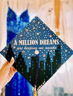 Highschool graduation cap decorated with blue sparkle base, black chrome of city sillputee, with silver Starr’s reading “a million dreams are keeping me awake” and “AMDA” in white font. Graduation Cap Decoration Diy, High School Graduation Cap