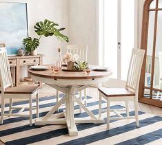 a dining room table with two chairs and a potted plant on the table in front of it