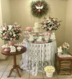 a table topped with lots of cakes and cupcakes next to vases filled with flowers