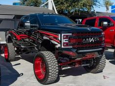 a black truck with red wheels parked next to other trucks