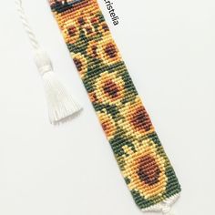 a cross stitch bookmark with sunflowers on it and a tassel hanging from the end