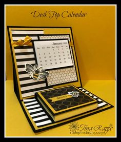 a desk top calendar sitting on top of a yellow table next to a black and white box