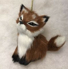 a brown and white stuffed animal ornament hanging from a string on a snow covered ground