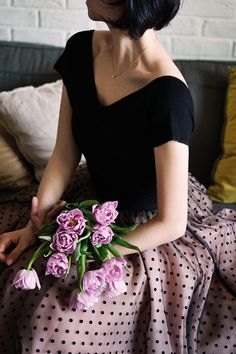 a woman sitting on a couch holding a bouquet of flowers