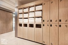 a large wooden locker filled with lots of white towels next to a wall full of linens