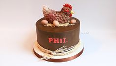 a chocolate cake decorated with a chicken and eggs on top is sitting on a white surface