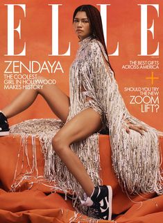 a woman sitting on top of an orange couch in front of a magazine cover with her legs crossed