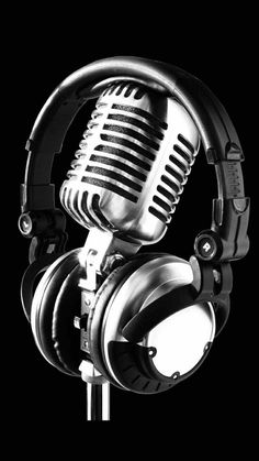 a microphone with headphones on top of it in black and white photo against a dark background