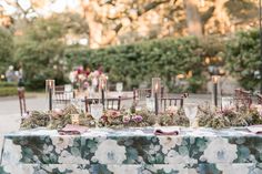 a table with flowers and candles is set up for an outdoor wedding reception at the park