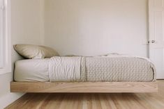 a bed sitting on top of a wooden floor next to a window