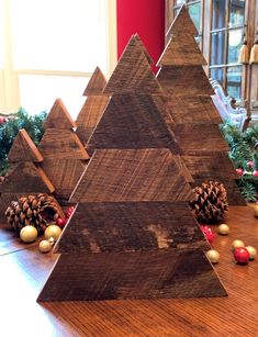 three wooden christmas trees sitting on top of a table next to pine cones and ornaments