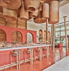 the interior of a restaurant with red walls and wooden ceiling lights hanging from the ceiling