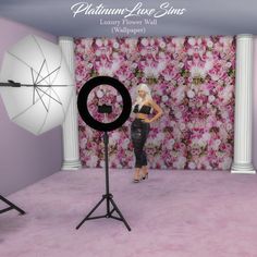 a woman is standing in front of a backdrop with pink flowers on it and an umbrella