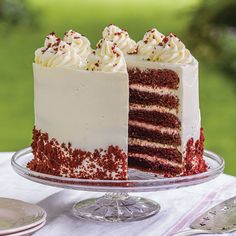 a red velvet cake with white frosting and sprinkles on a glass plate