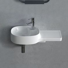 a white sink sitting next to a wall mounted faucet on a gray wall