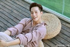 a young man sitting on top of a wooden floor next to a basket filled with fruit