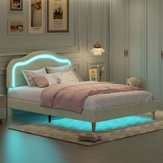 a white bed with blue lights on the headboard and foot board in a bedroom