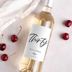 a bottle of wine sitting on top of a table next to some cherries and a napkin