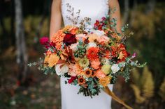 a woman holding a bouquet of flowers in her hands and wearing a white wedding dress