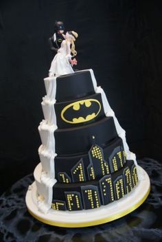 a batman themed wedding cake with the bride and groom on top, surrounded by city lights