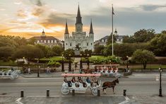 a horse drawn carriage traveling down a street next to a tall building with spires