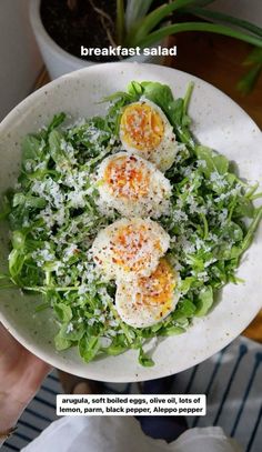 a person holding a white bowl with some food in it and the words breakfast salad above it