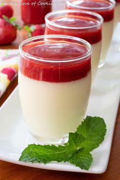 three glasses filled with yogurt and garnished with fresh mint on a white plate