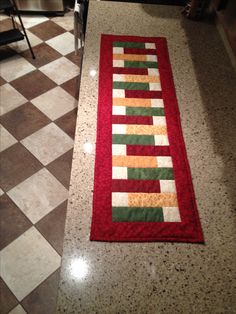 a red and green rug sitting on top of a kitchen floor next to a stove