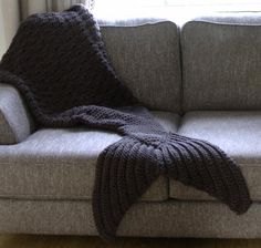 a couch with a knitted blanket on it and a window in the back ground