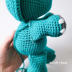 a crocheted blue teddy bear is being held up by someone's hand