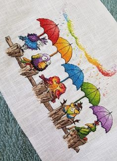 the cross stitch pattern shows several different colored umbrellas on a white cloth with green grass in the background