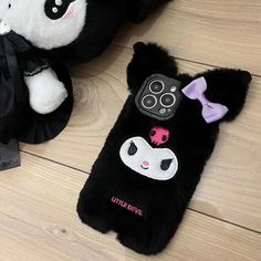 two black and white stuffed animals laying next to each other on a wooden floor in front of a cell phone case