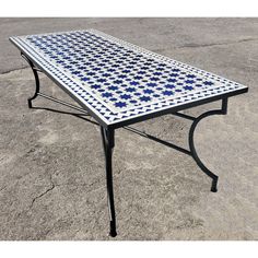 a table with blue and white tiles on it sitting in the middle of a parking lot