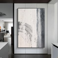 an abstract painting hangs on the wall in a modern living room with white walls and black accents