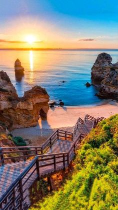 the sun is setting over the ocean and some steps lead down to the beach area