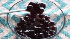 a glass bowl filled with cherries on top of a blue and white table cloth