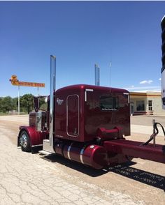 a red semi truck parked in front of a gas station with a sign on it's side