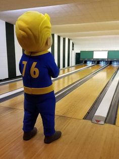 a person in a blue and yellow outfit standing on a bowling alley with bowling pins