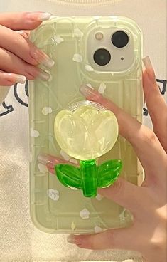 a hand holding an iphone case with a green flower on the front and back cover