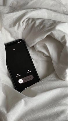 an iphone laying on top of a bed covered in white sheets