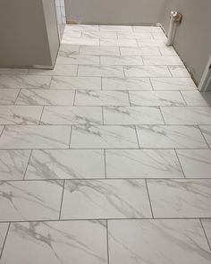 a bathroom with white marble tile floors and walls, along with a toilet in the corner