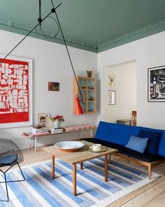 a living room filled with furniture and paintings on the wall next to a blue couch