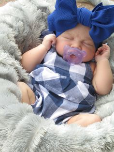 a newborn baby wearing a blue bow laying in a blanket