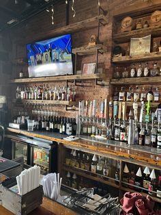 a bar with lots of liquor bottles on the shelves and a television in the background