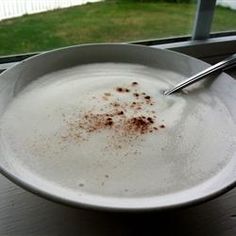 a white bowl filled with food sitting on top of a table next to a window